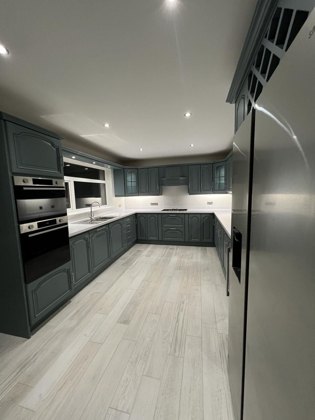 a kitchen with gray cabinets , stainless steel appliances , and a stainless steel refrigerator .