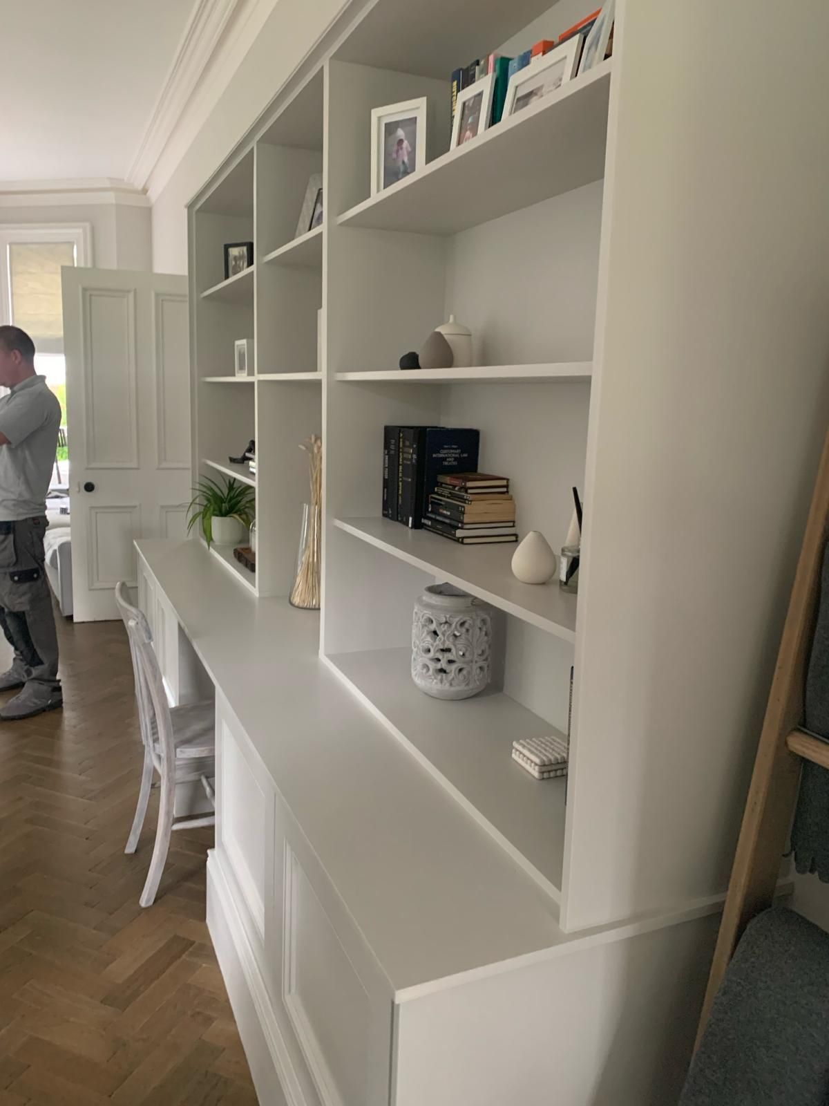 a man is standing in front of a bookshelf in a living room .