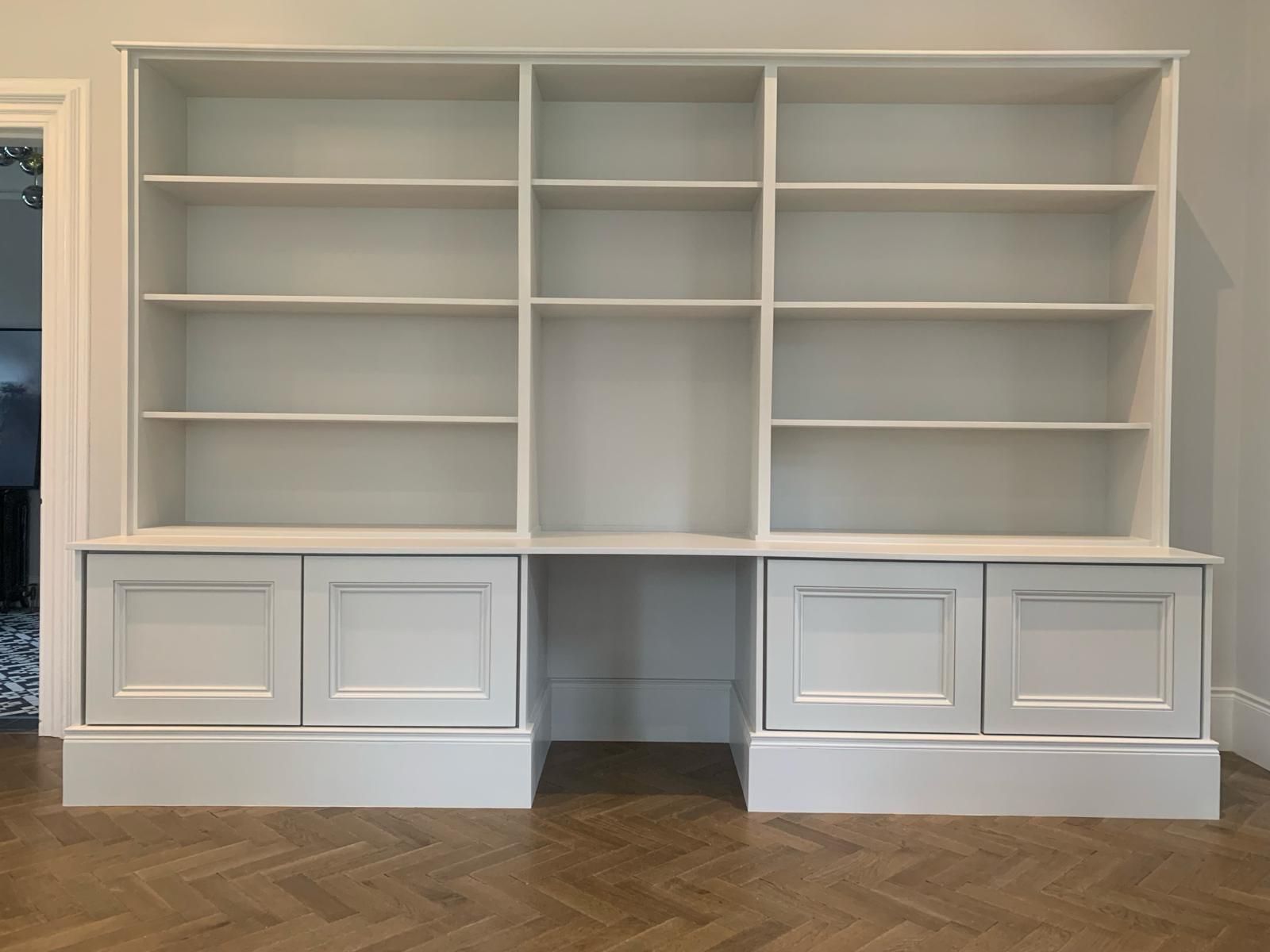 a white bookshelf with a desk underneath it in a room .
