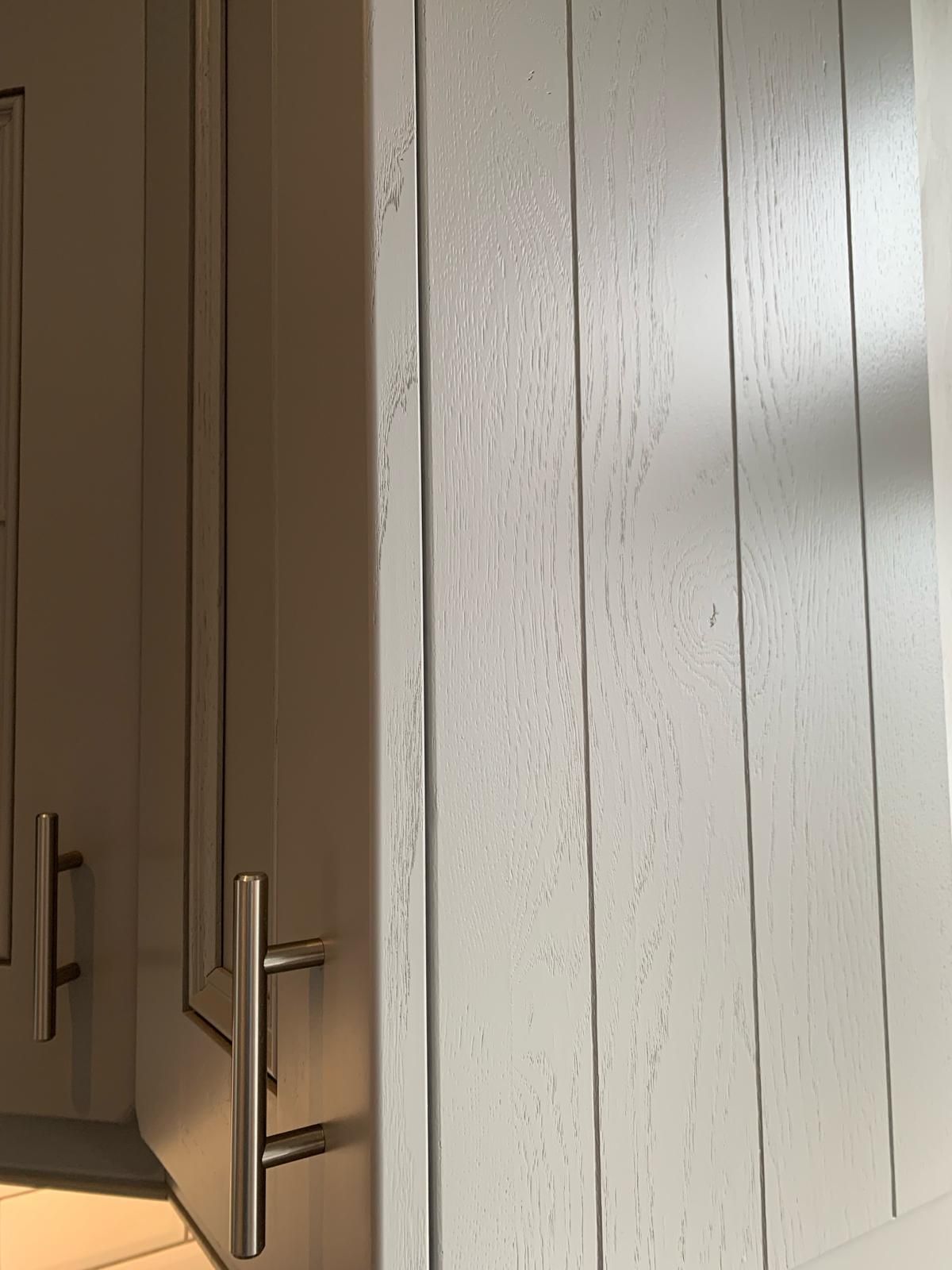 a close up of a white cabinet with a stainless steel handle .