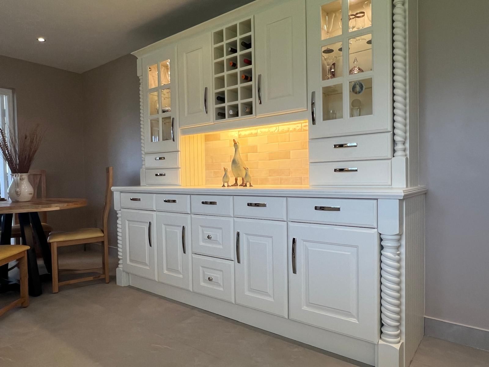 A kitchen with white cabinets and a wine rack