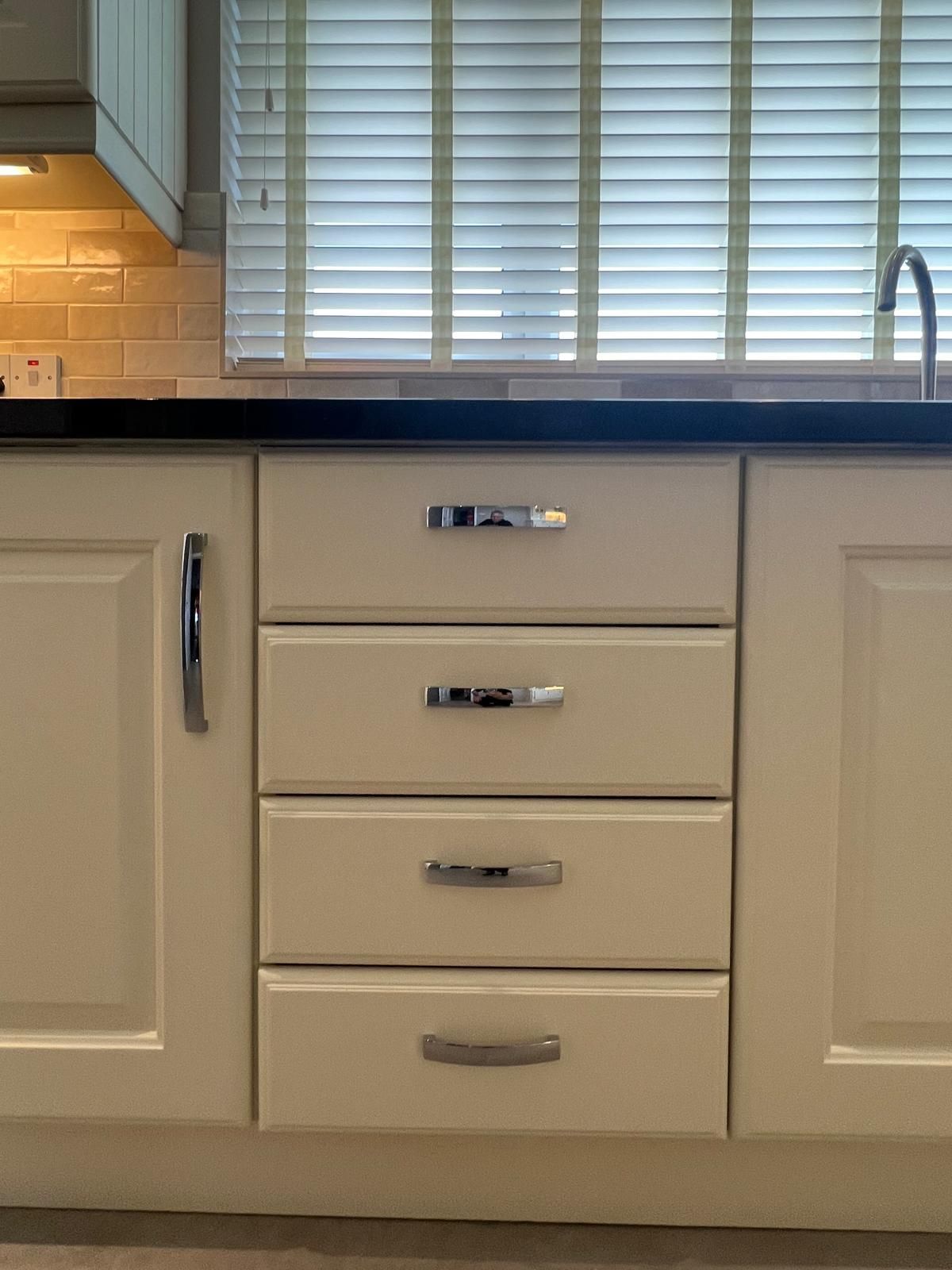 A kitchen with white cabinets and drawers and a sink.