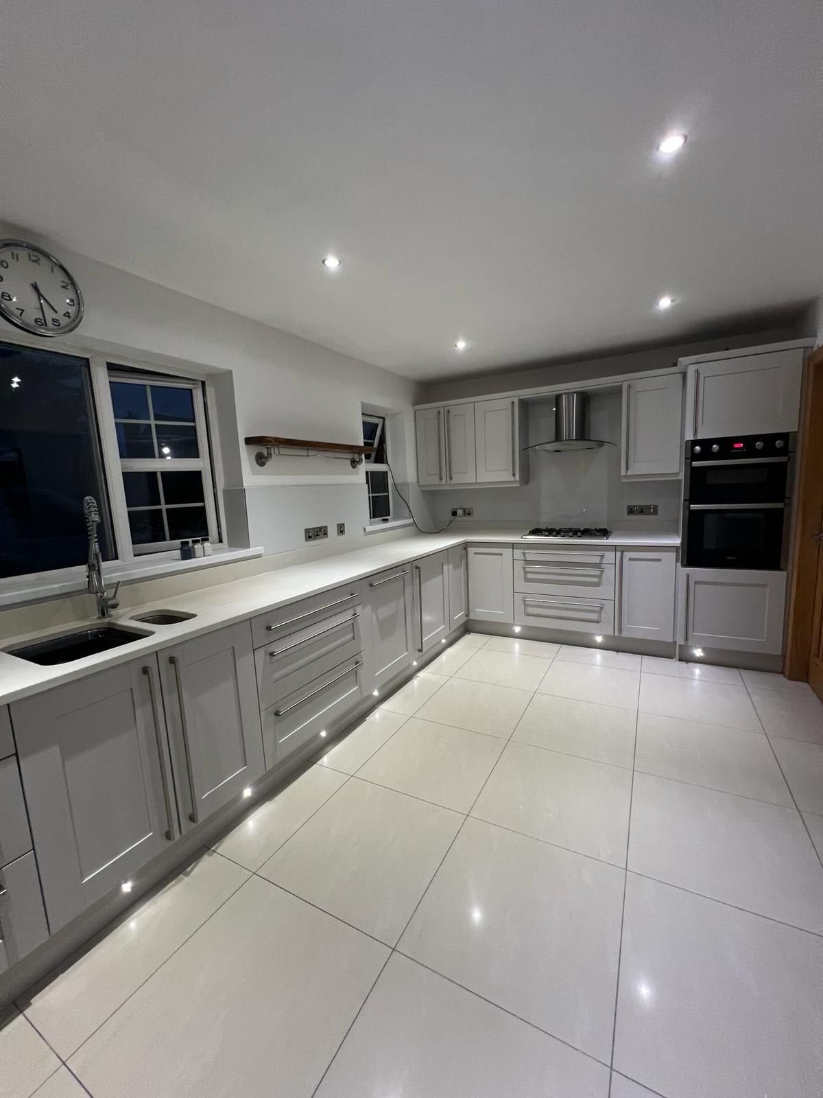 a kitchen with white cabinets and a clock on the wall .