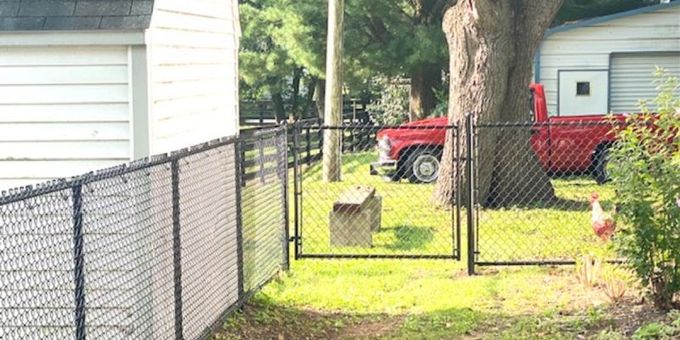 A red truck is parked in front of a chain link fence.