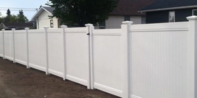 A white fence with a gate in front of a house.