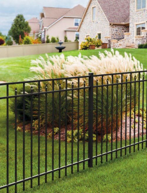 A wrought iron fence surrounds a lush green yard in front of a house