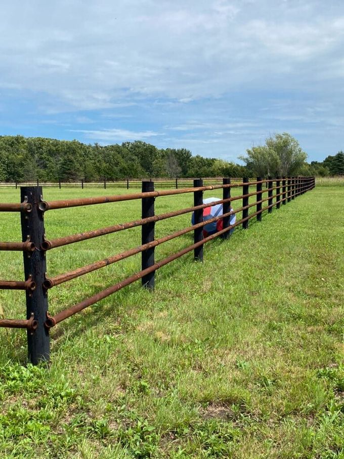 A wooden fence surrounds a grassy field.