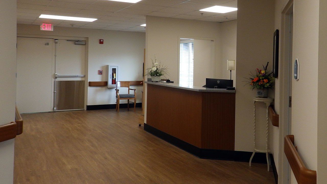 A hallway with a wooden floor and a reception desk in a hospital.