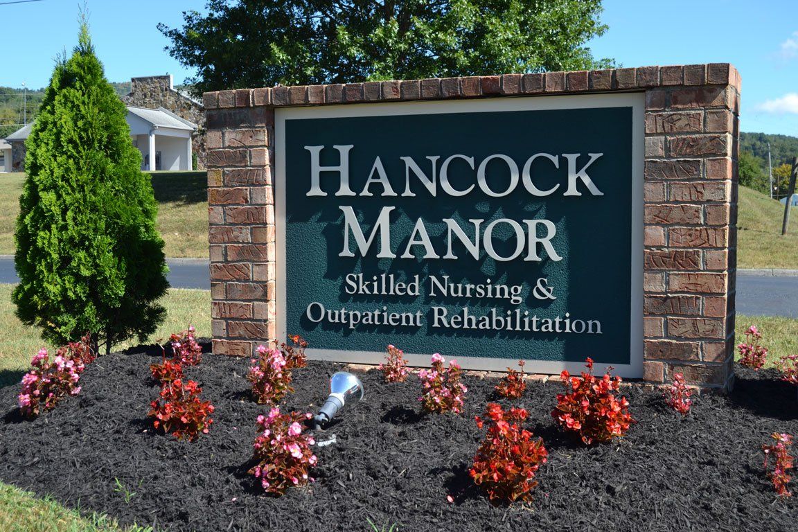 A sign for hancock manor skilled nursing and outpatient rehabilitation