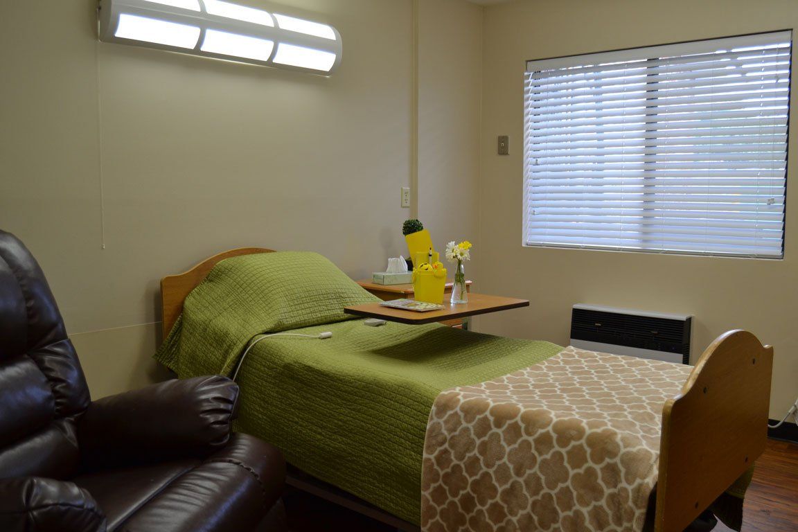 A bedroom with a bed , chair and window with blinds.