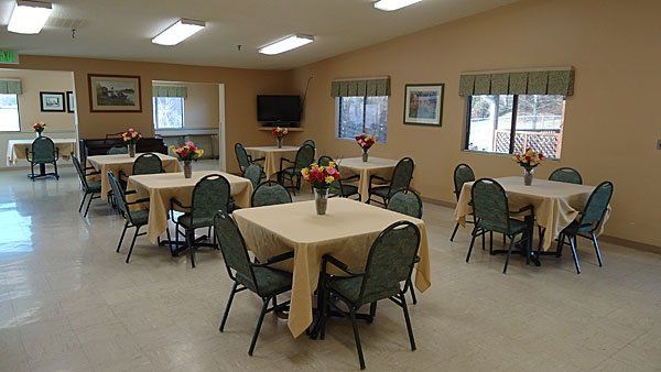 A large room with tables and chairs and flowers on them