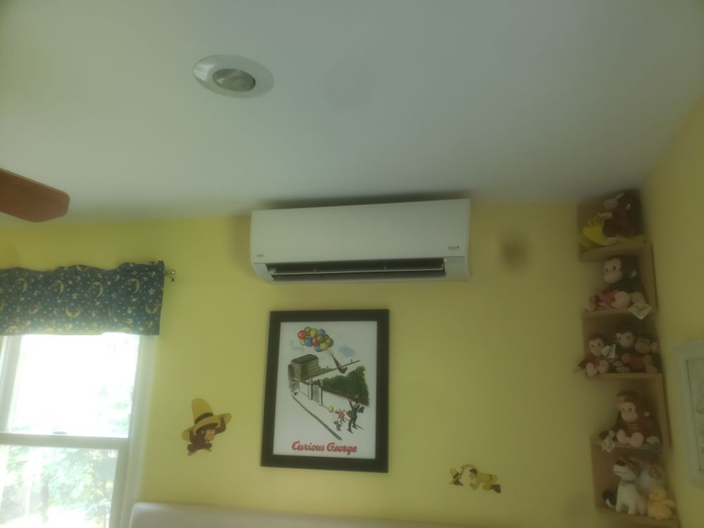 A yellow-walled bedroom with a mini-split AC unit, a 