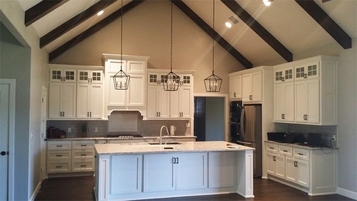 Remodeled kitchen with white cabinets and black, modern pendant lighting
