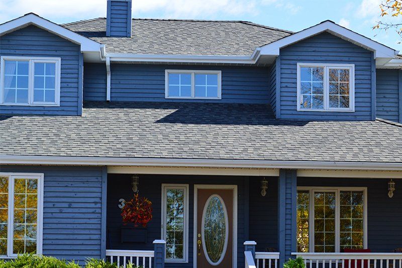 Large home with blue siding and repaired roof by Greenhagen Homes