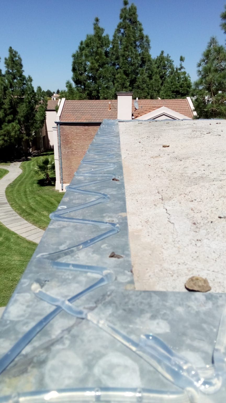 Persona con un arnés de seguridad en un ascensor, aplicando sellador a una viga de un edificio.