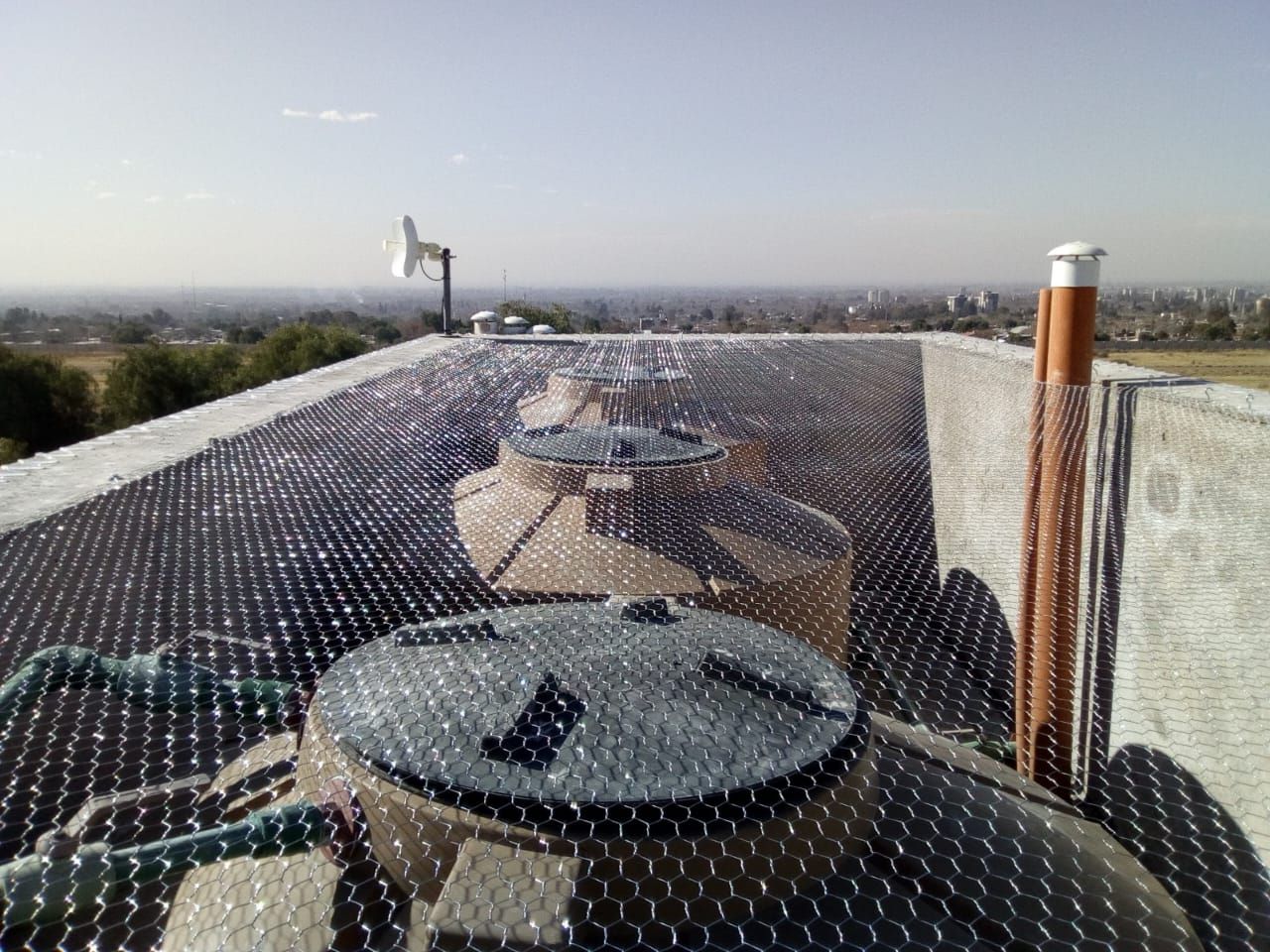 Azotea con tanques de agua cubiertos con una malla. También se ven una antena de radio y conductos de ventilación.