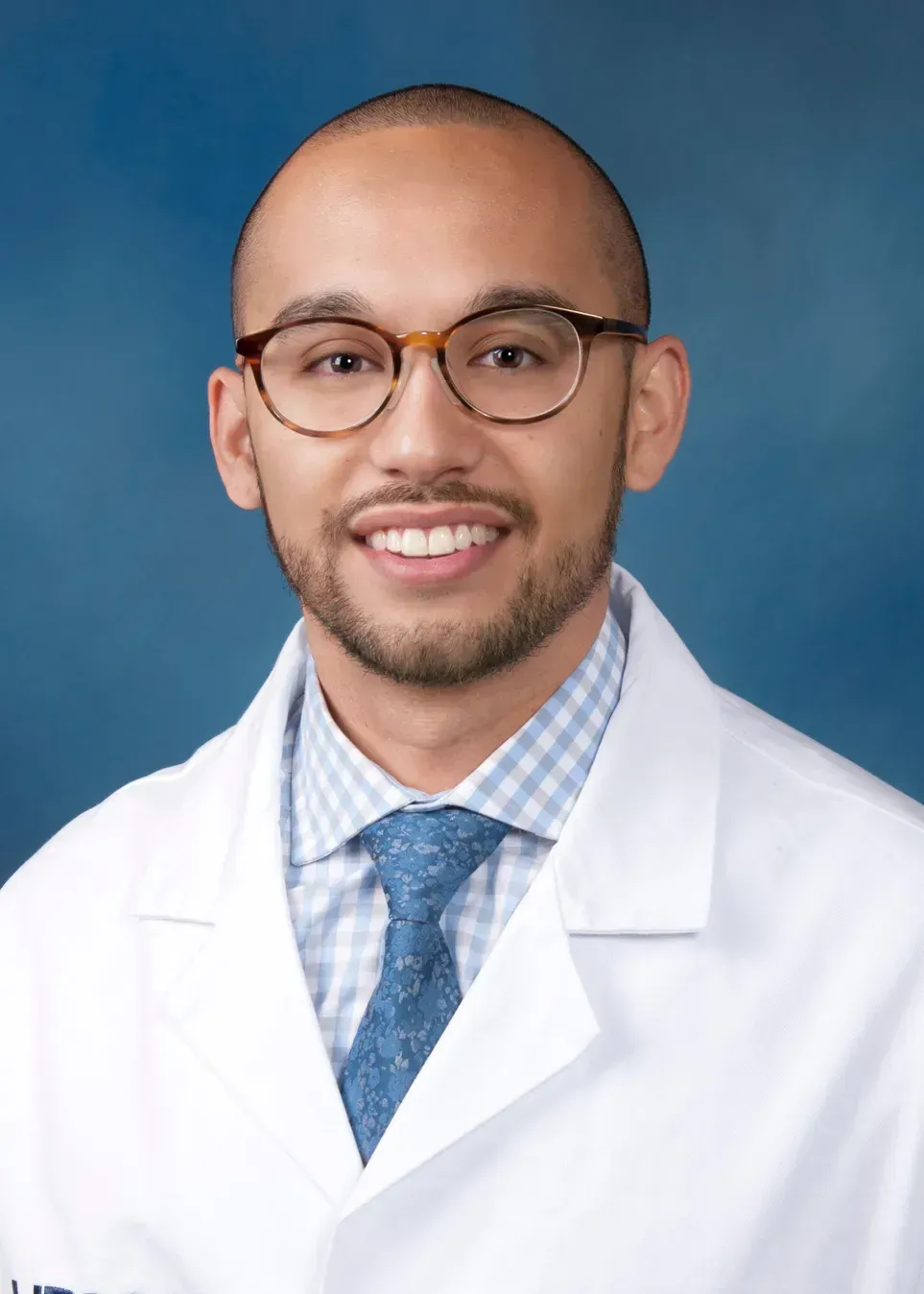 A smiling doctor in a lab coat with a stethoscope around his neck.
