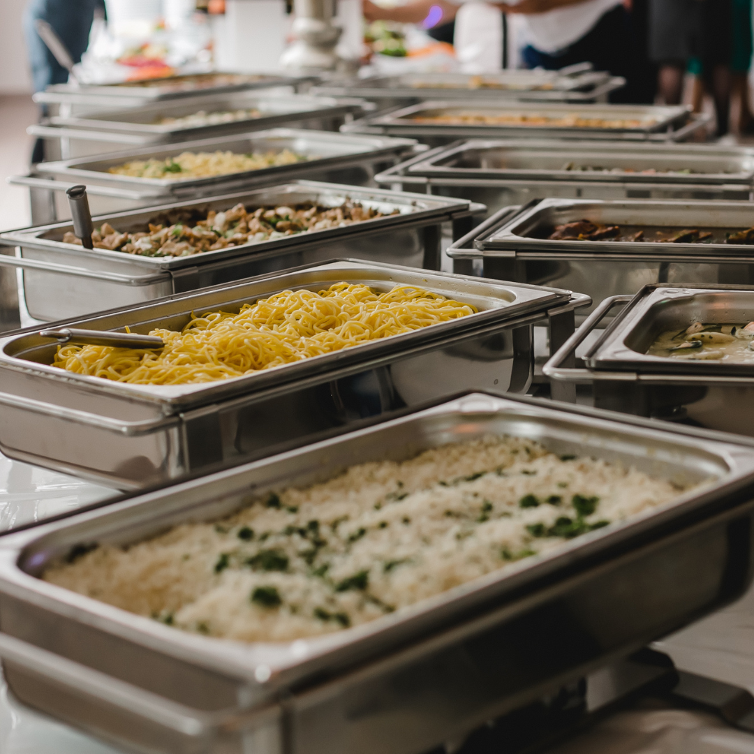 There are many trays of food on the table.
