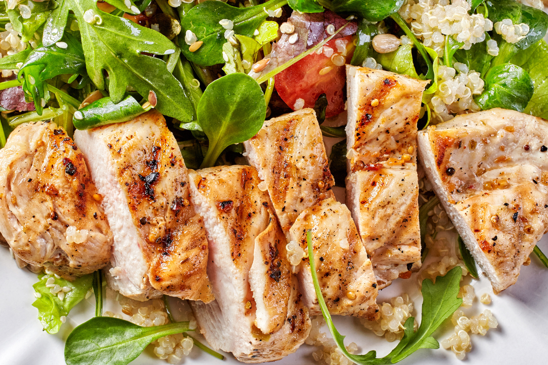 A white plate topped with grilled chicken and a salad.