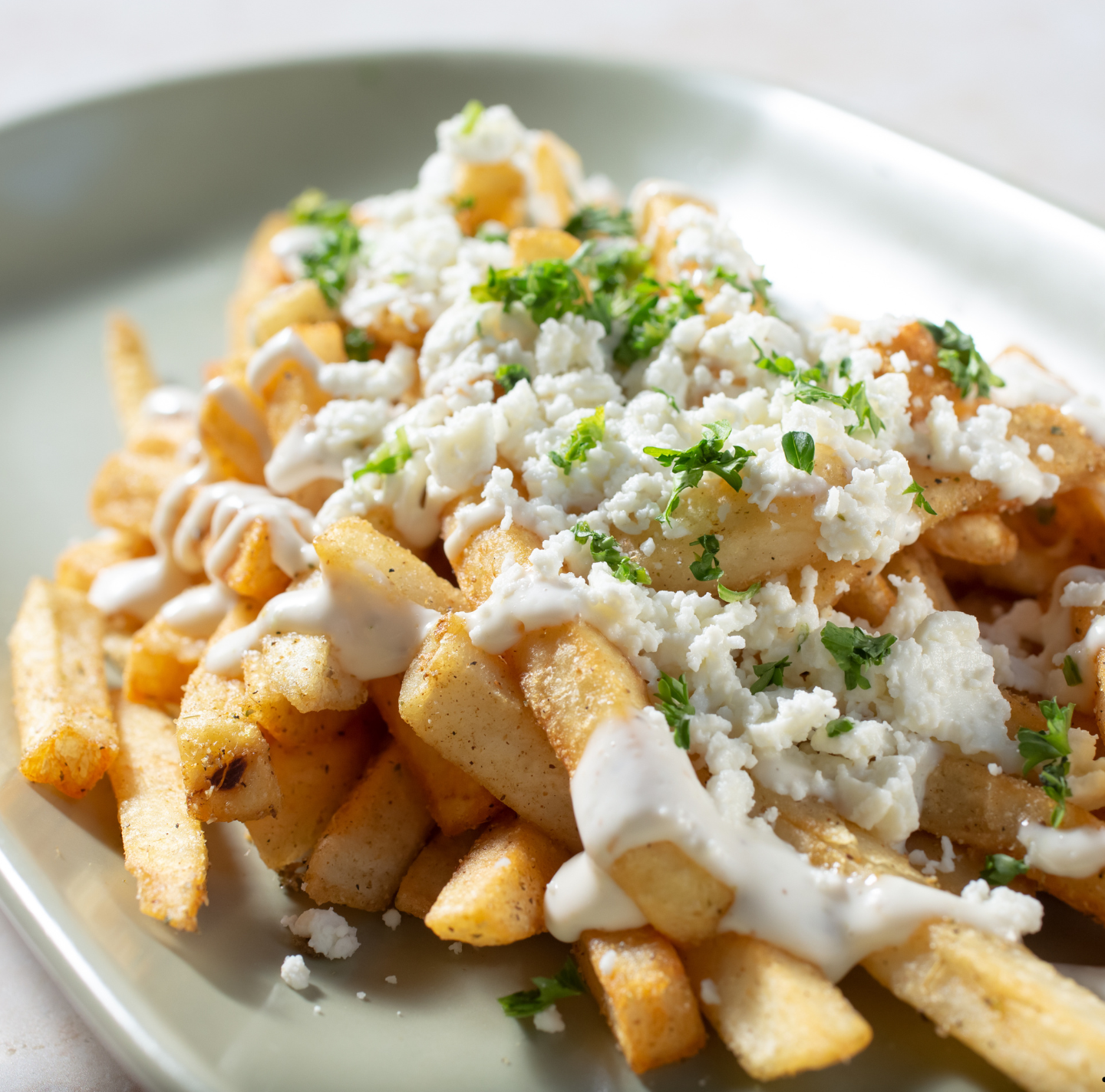 A plate of french fries with cheese and sauce on top