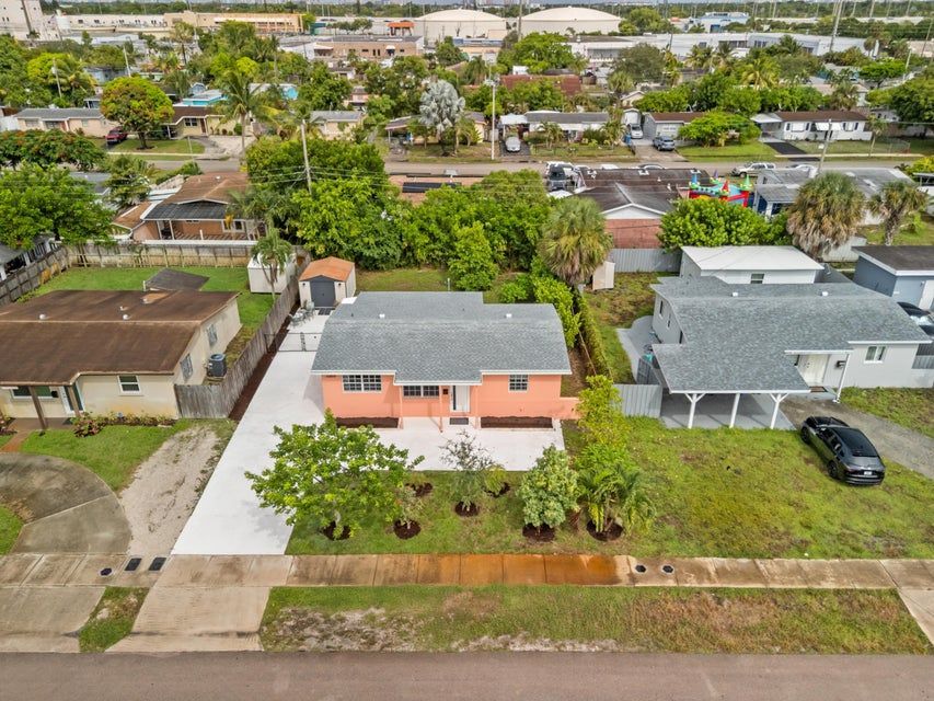 Aerial view of a single-story coral-colored home at 4200 NW 12th Avenue, Oakland Park, Florida, with a wide driveway, front yard trees, and surrounding neighborhood homes.