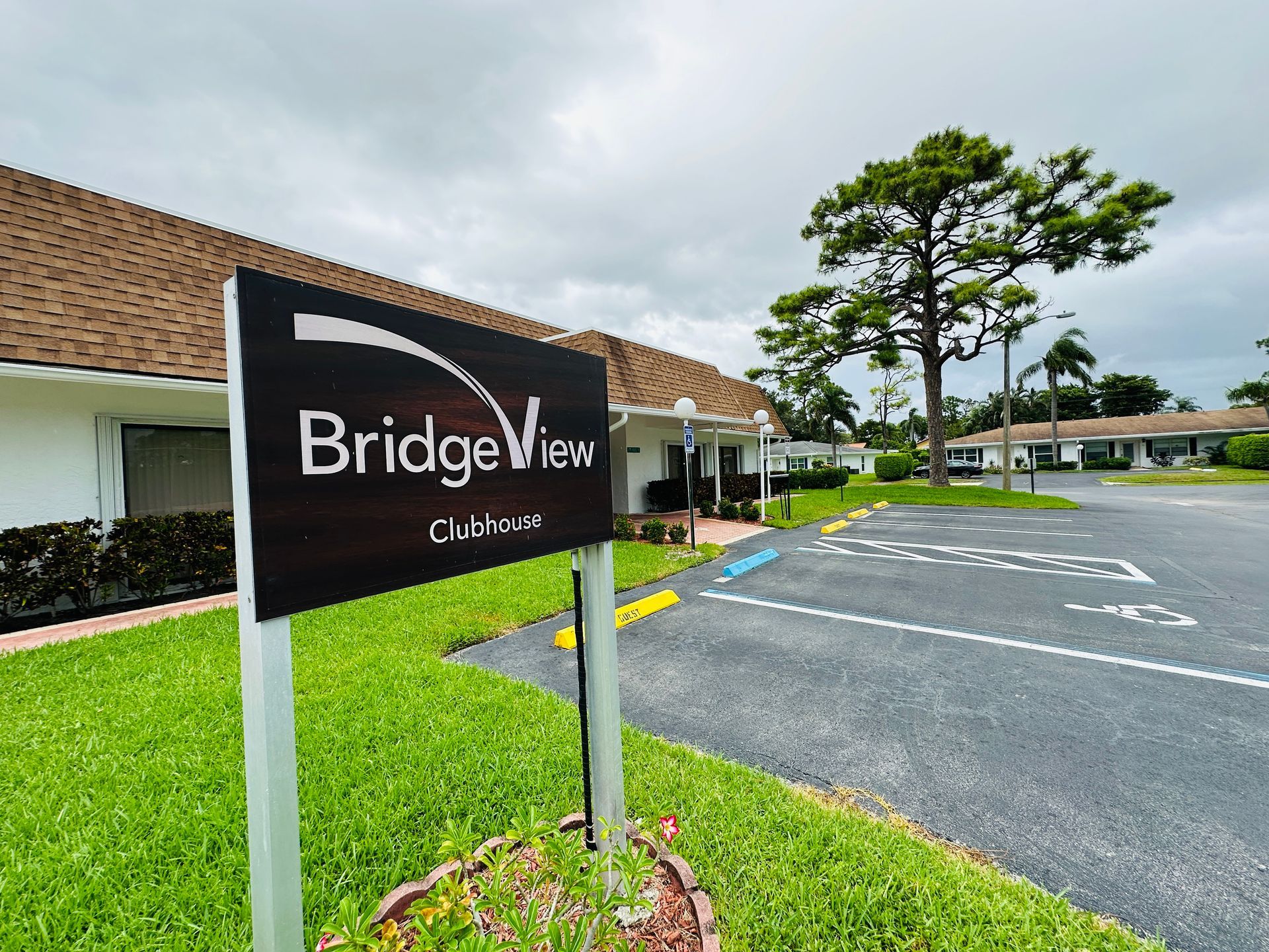Sign for Bridgeview community in front of a building and a cloudy sky.