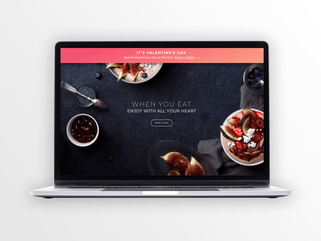 Laptop displaying a food website with bowls of food and figs on a dark background.