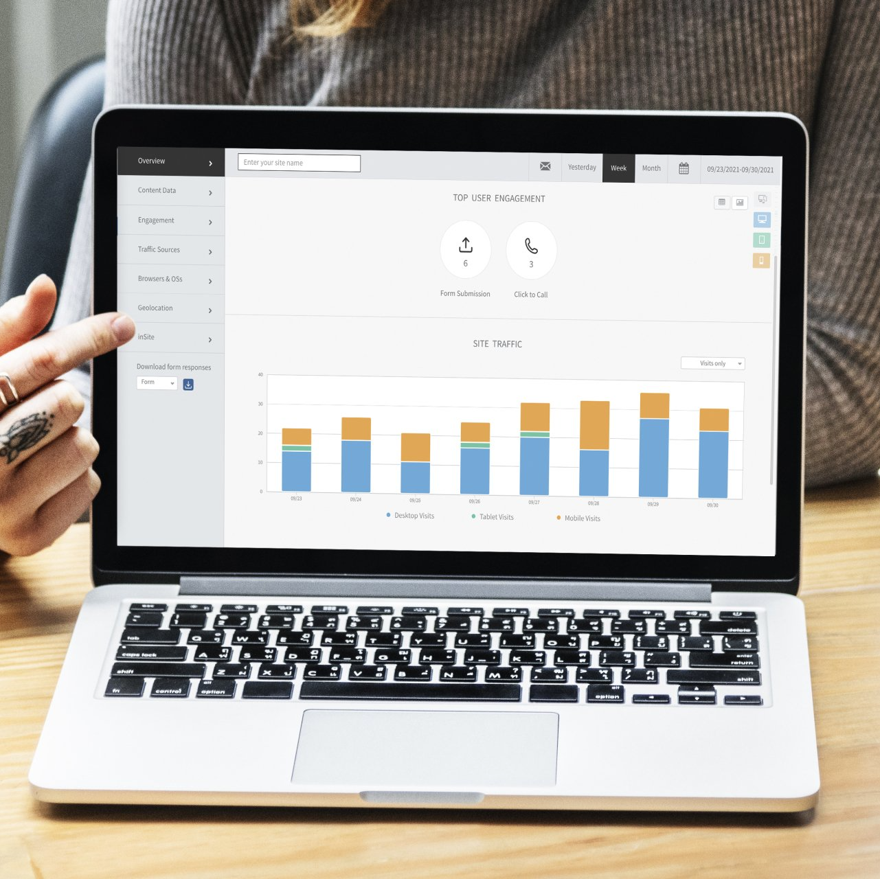 Person pointing at a laptop screen displaying a bar graph; light blue and gold bars, data analysis.
