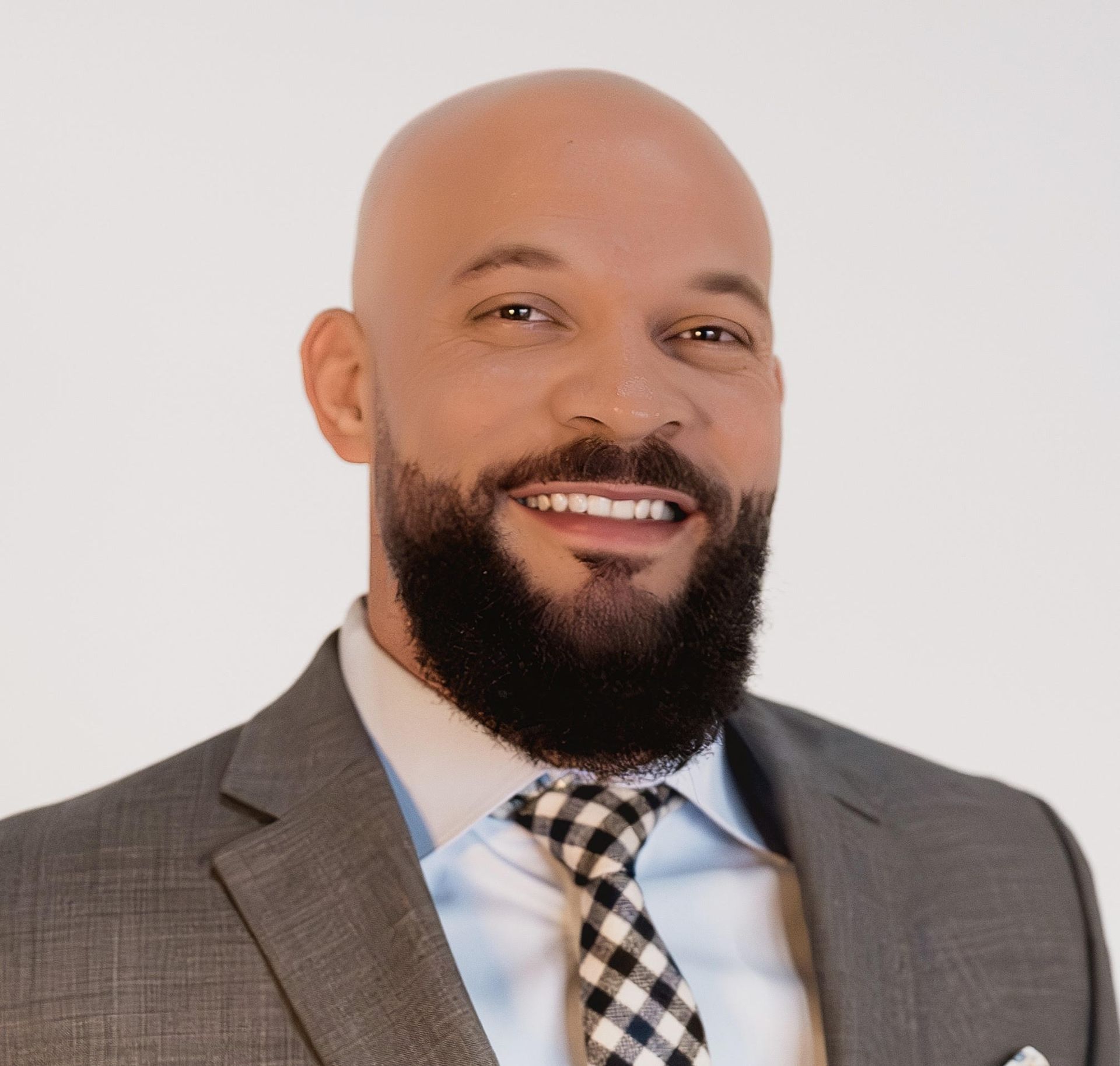 A bald man with a beard wearing a suit and tie