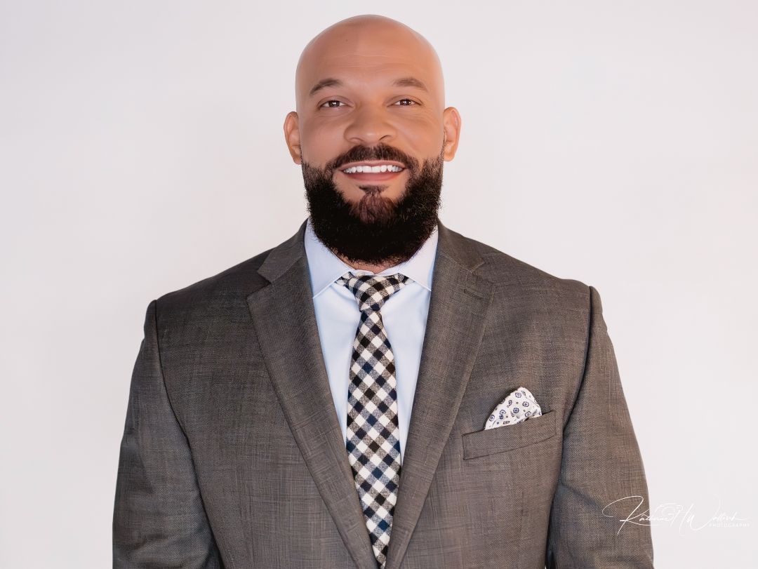 A bald man with a beard wearing a suit and tie