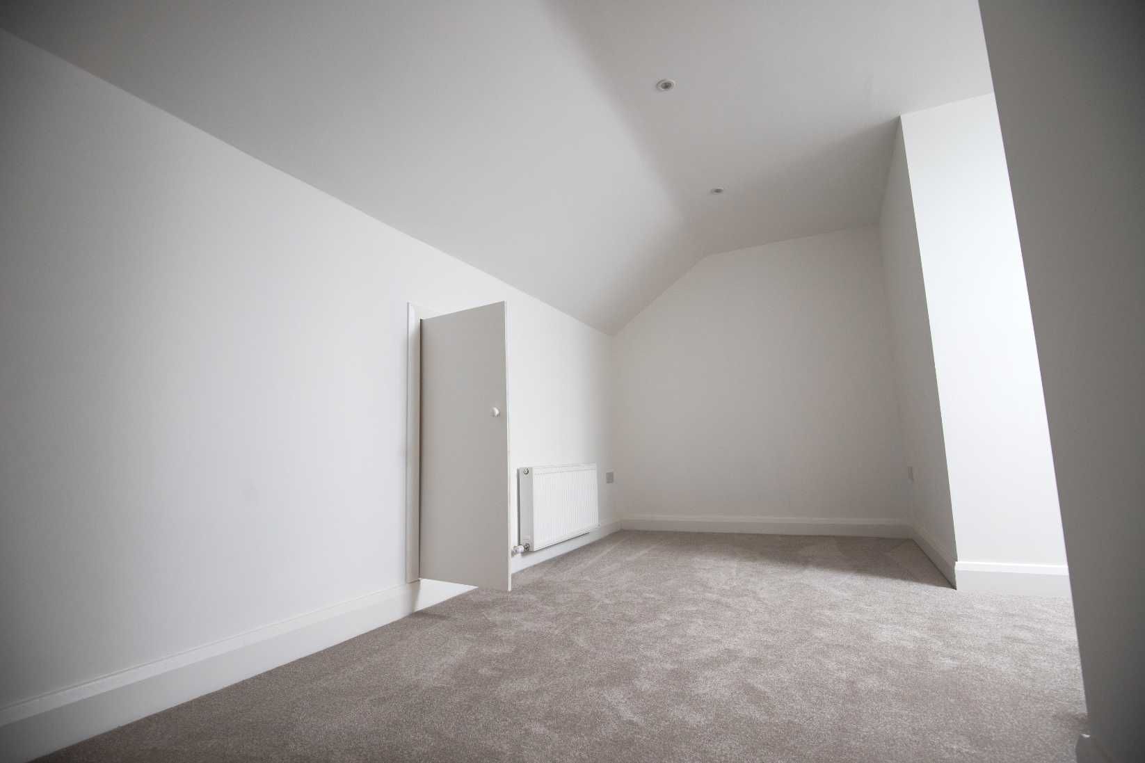 An empty room with a slanted ceiling and a door