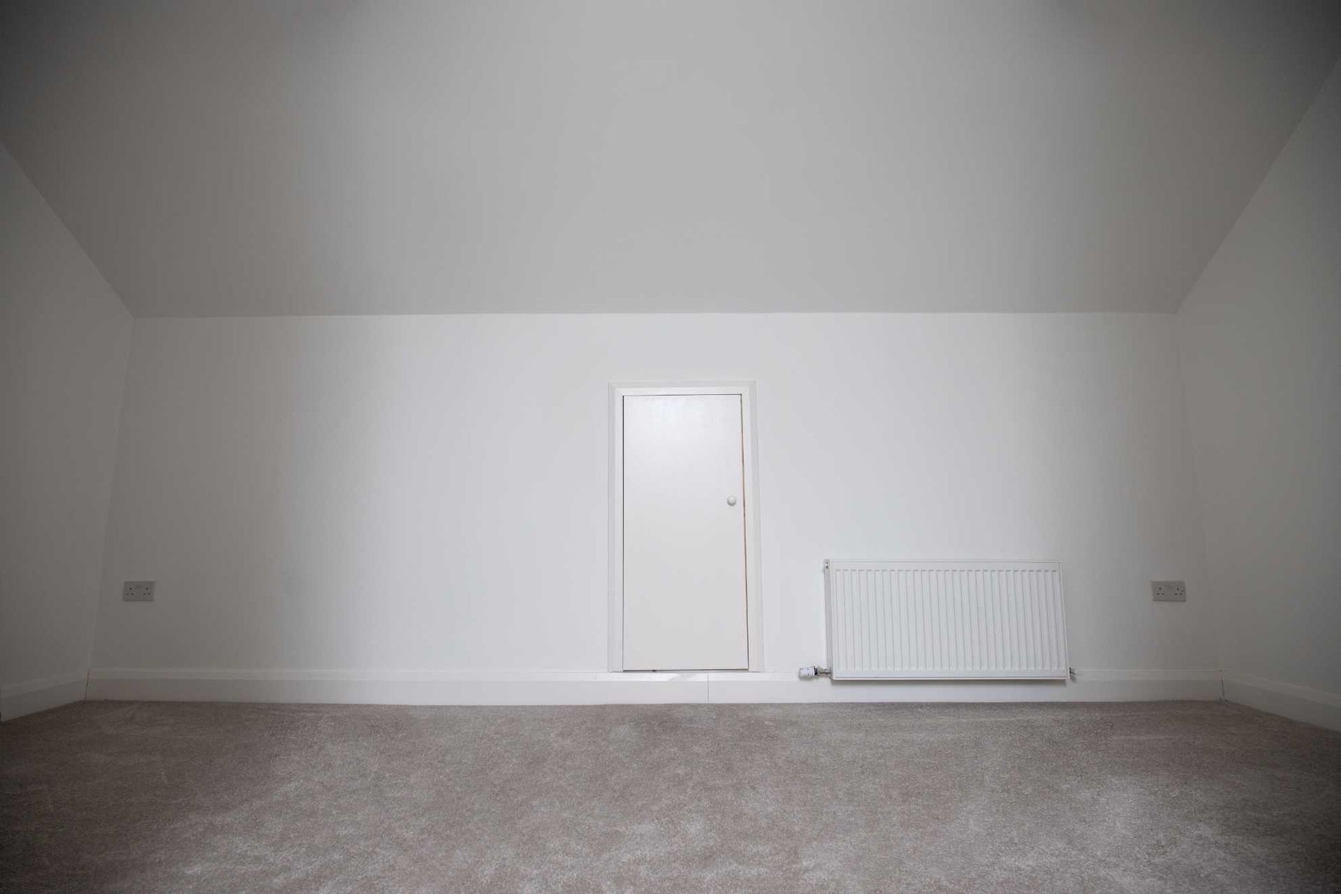 An empty room with a door and a radiator.