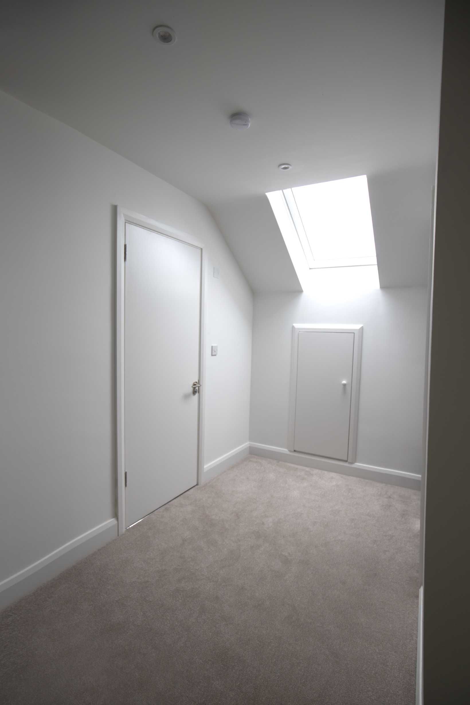 An empty room with a skylight and a door