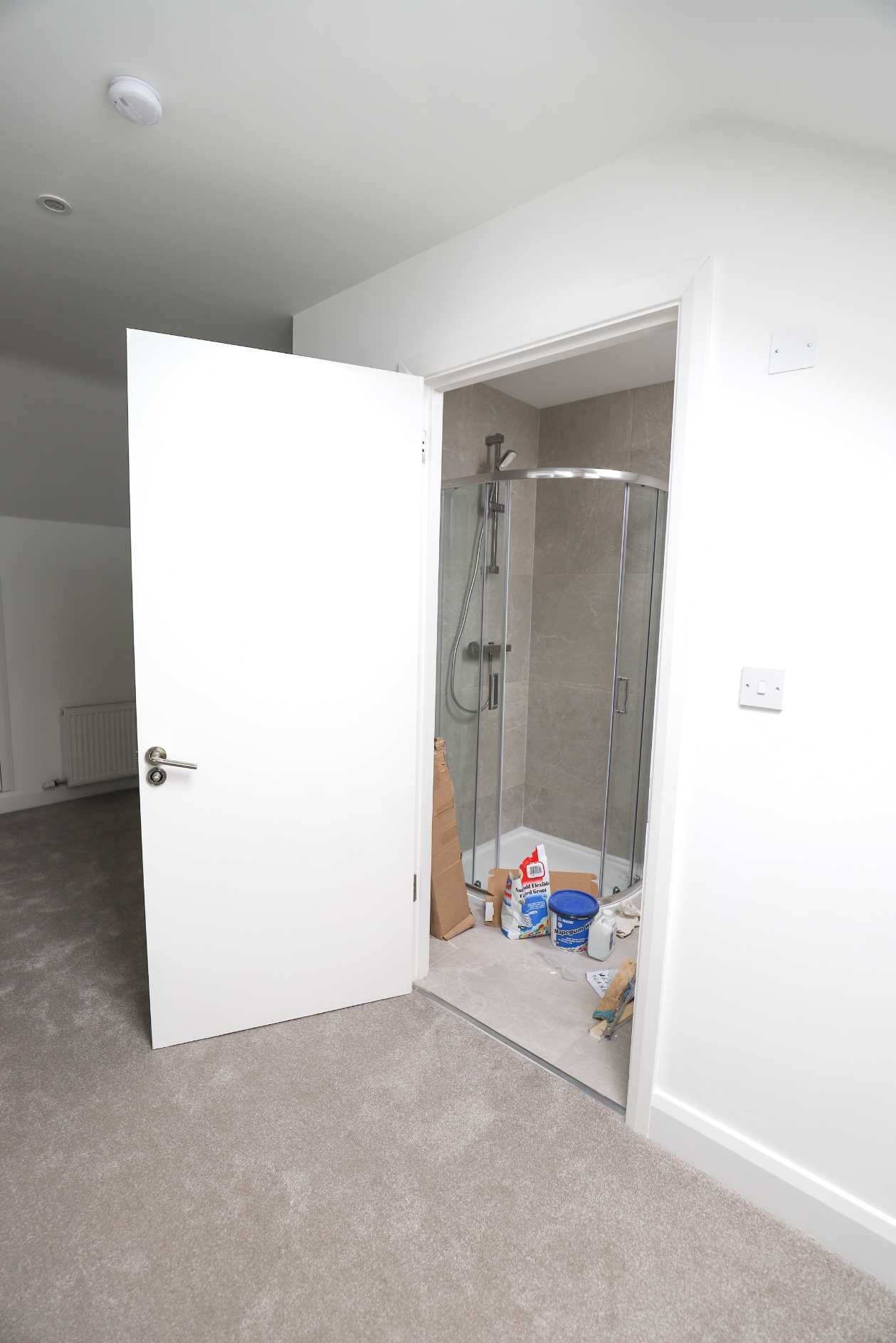 A bathroom with a walk in shower and a white door.