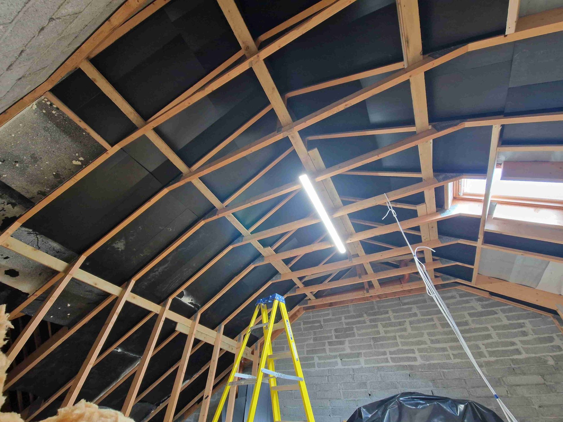 A ladder is sitting in the attic of a building.