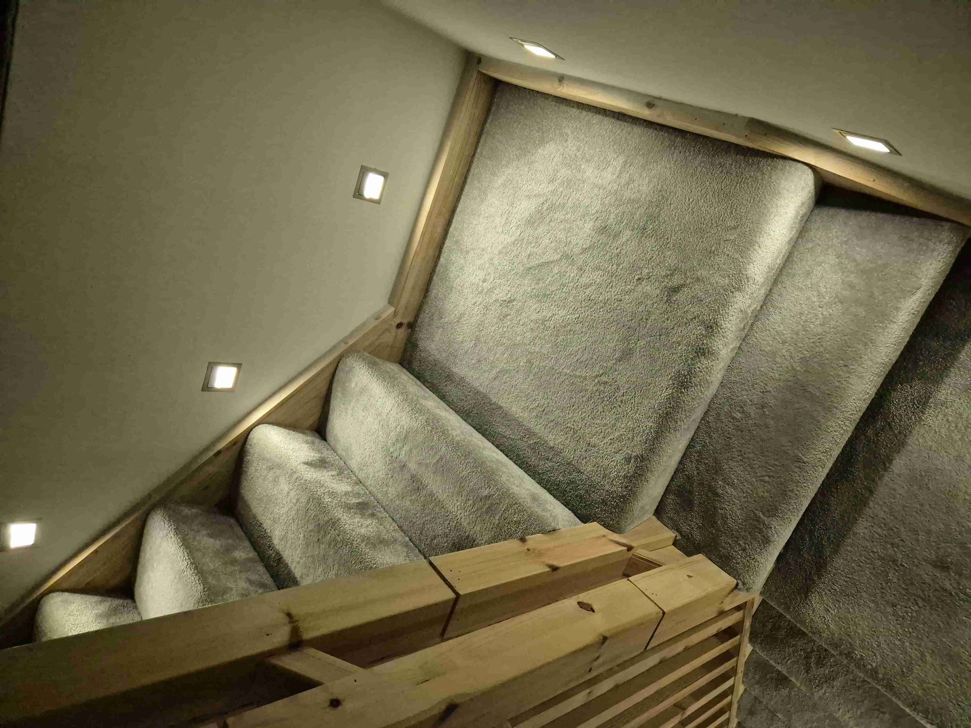 A staircase with a wooden railing and a couch on the bottom.