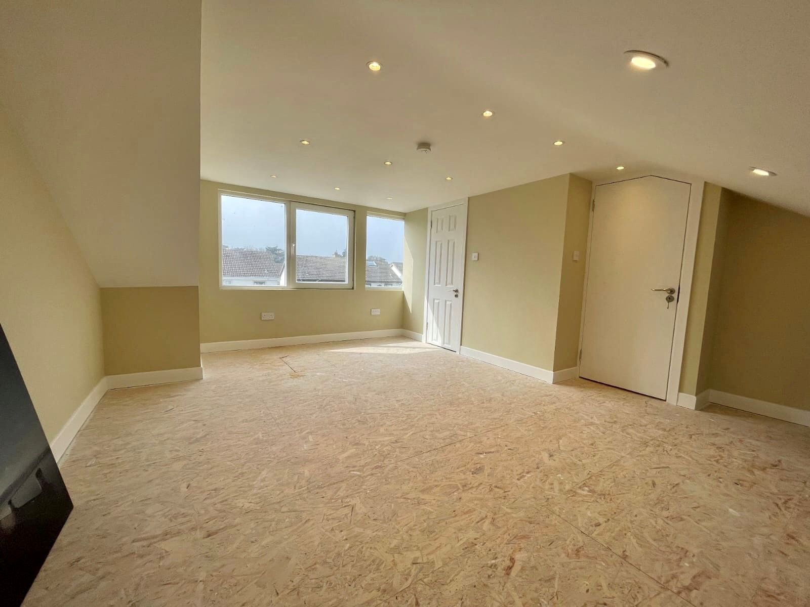 An empty room with a carpeted floor and a window.
