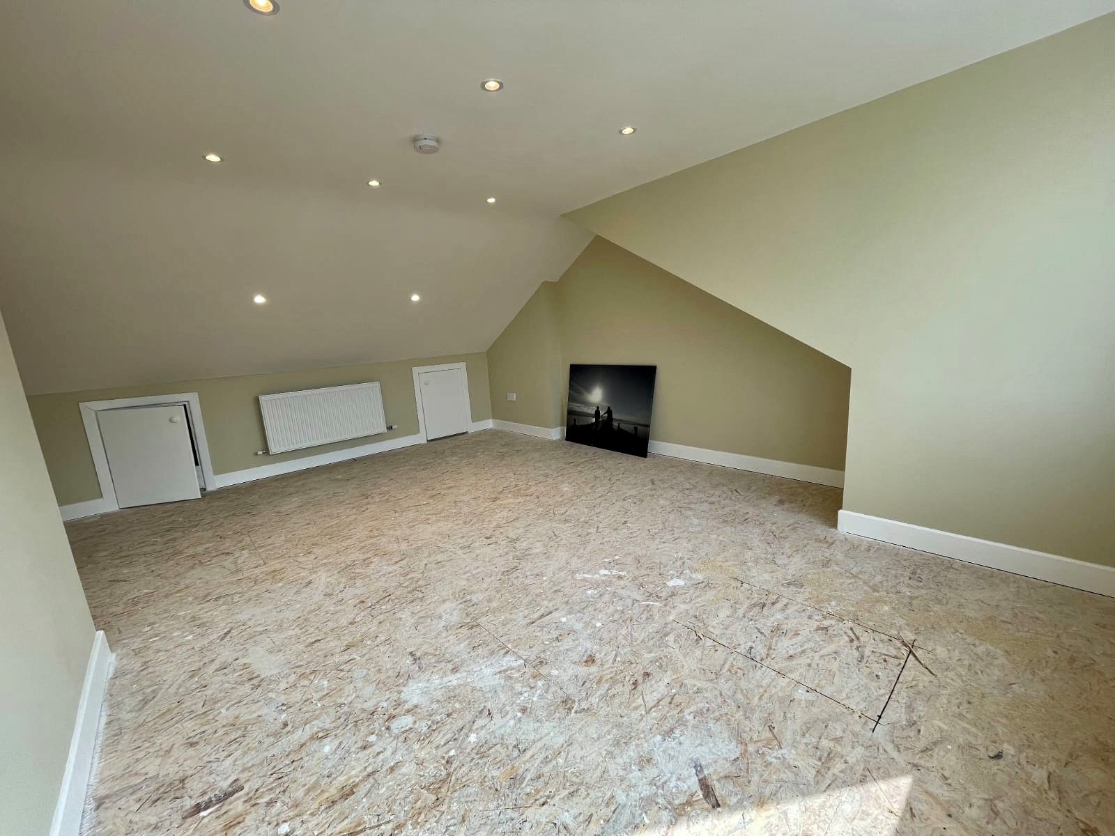 An empty room with a carpeted floor and a picture on the wall.