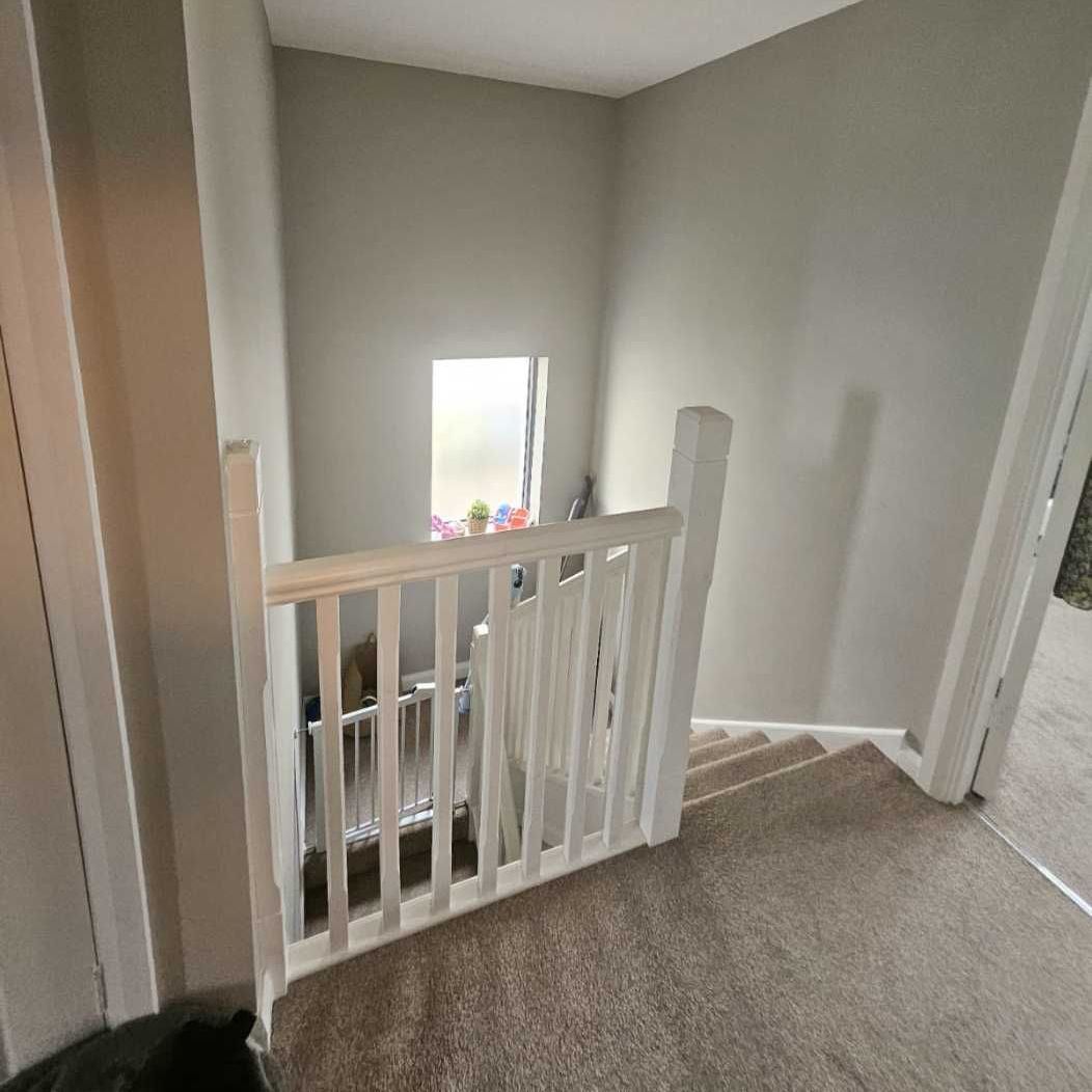 A staircase in a house with a white railing and a window.