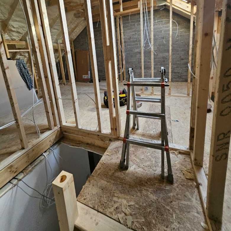 A ladder is sitting in the middle of a room under construction.