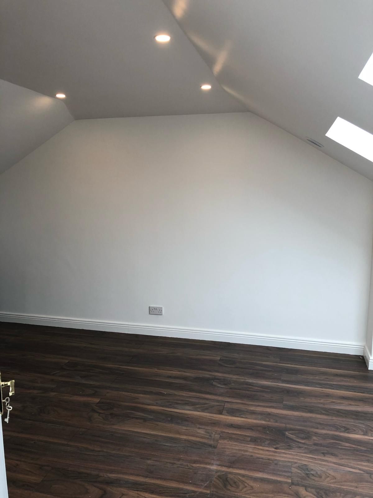 An empty room with a wooden floor and white walls.