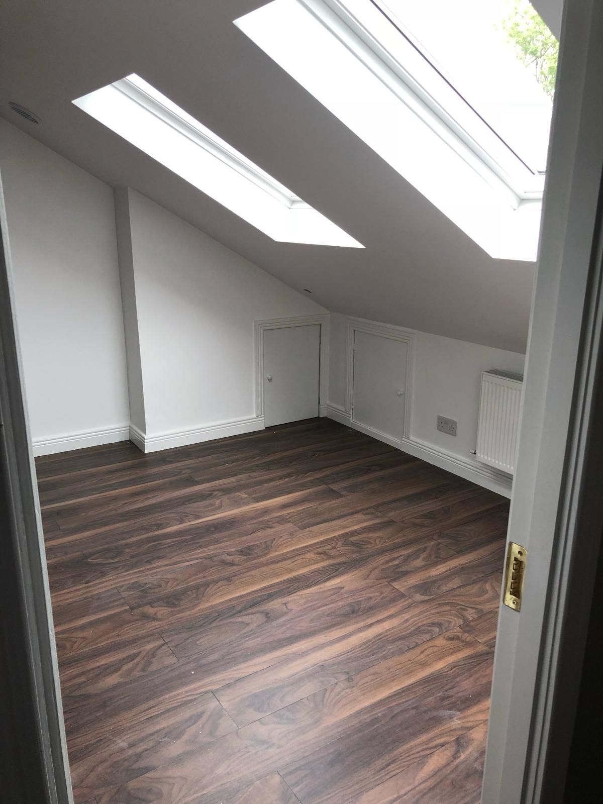 A room with a wooden floor and a skylight in the ceiling.