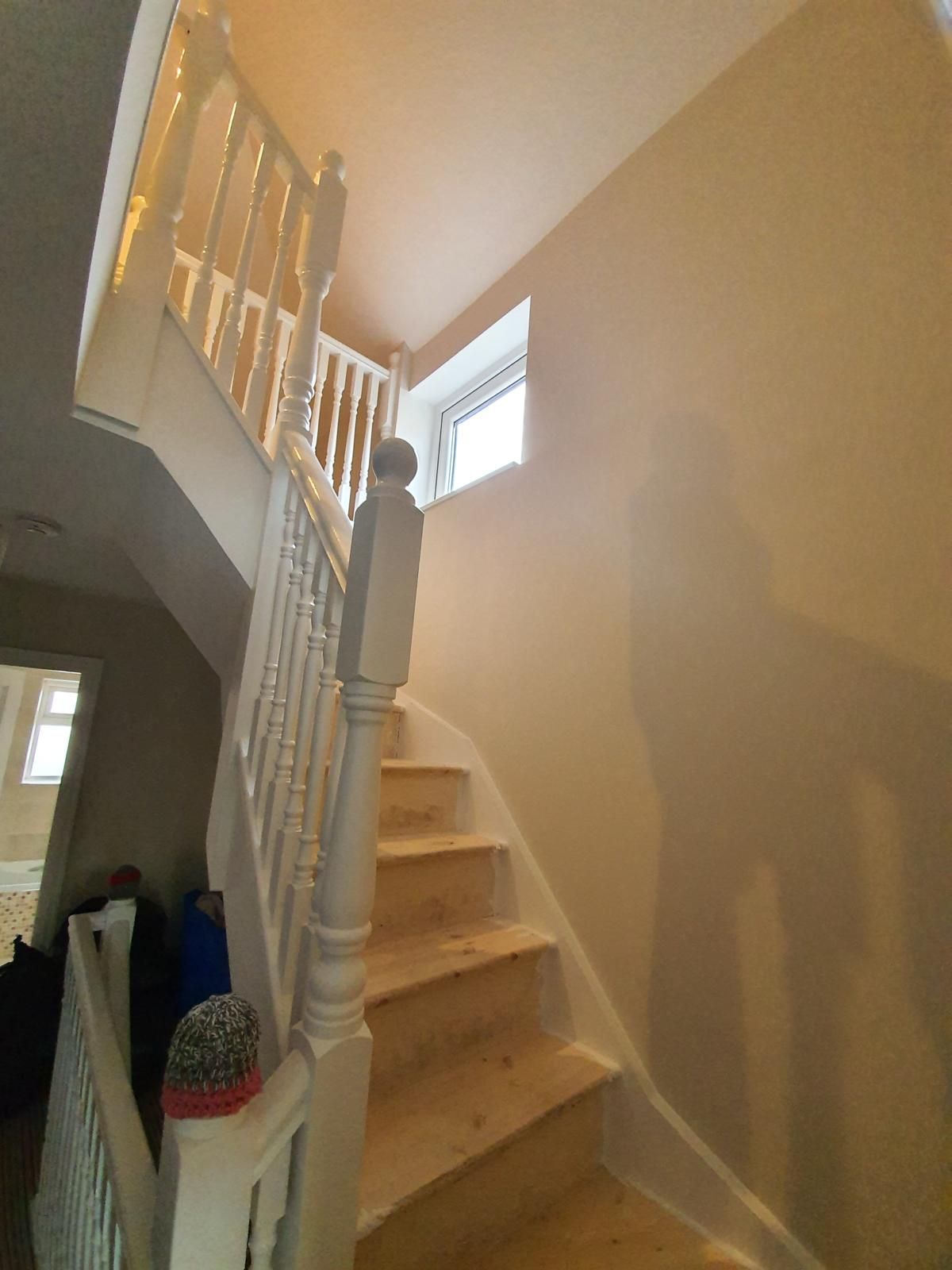 A wooden staircase with a white railing and a window.
