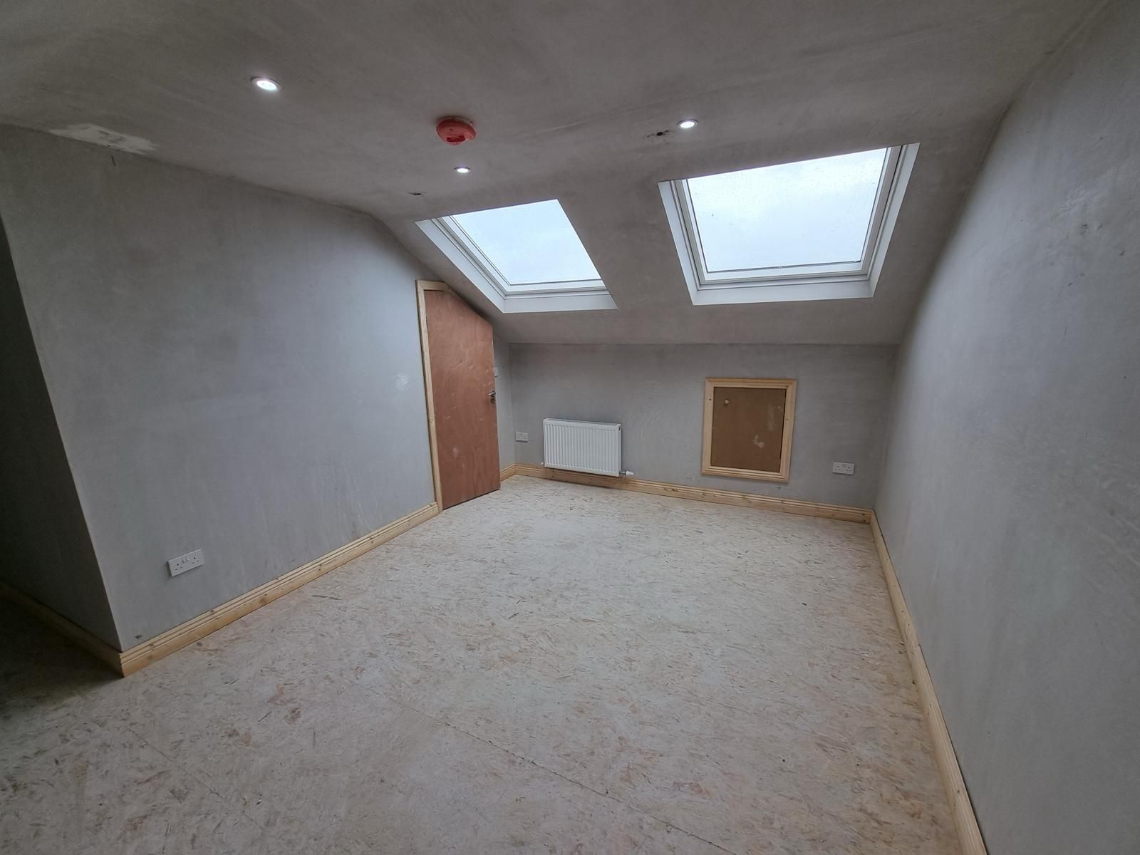 An empty room with two skylights on the ceiling.
