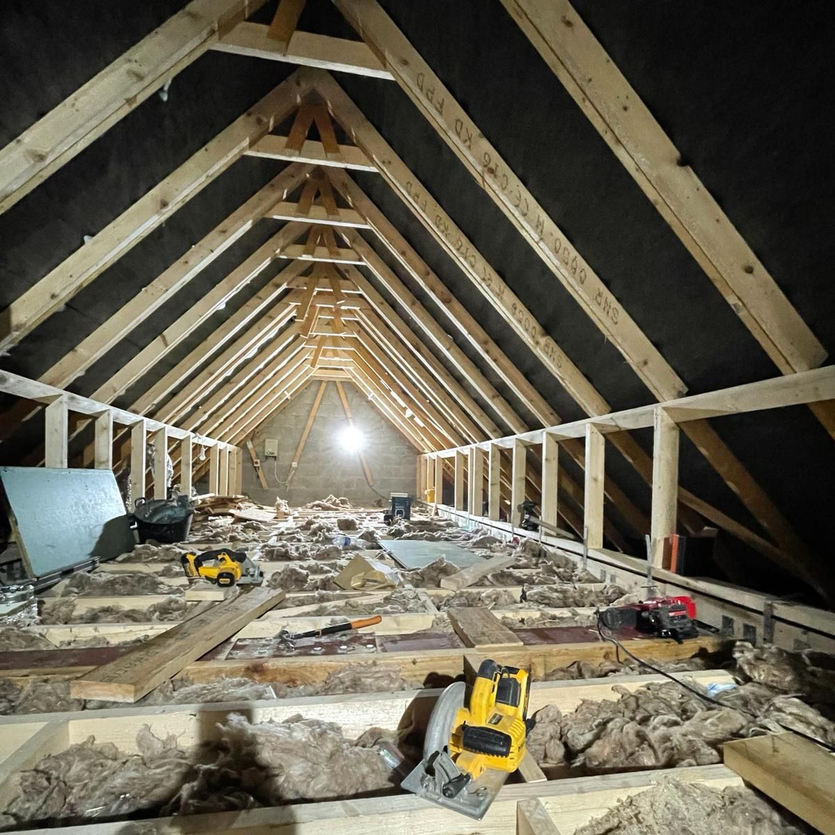 The attic of a house is being remodeled with wooden beams and insulation.