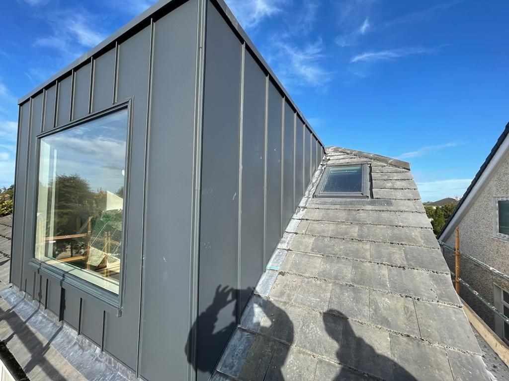 A person is taking a picture of the roof of a building.