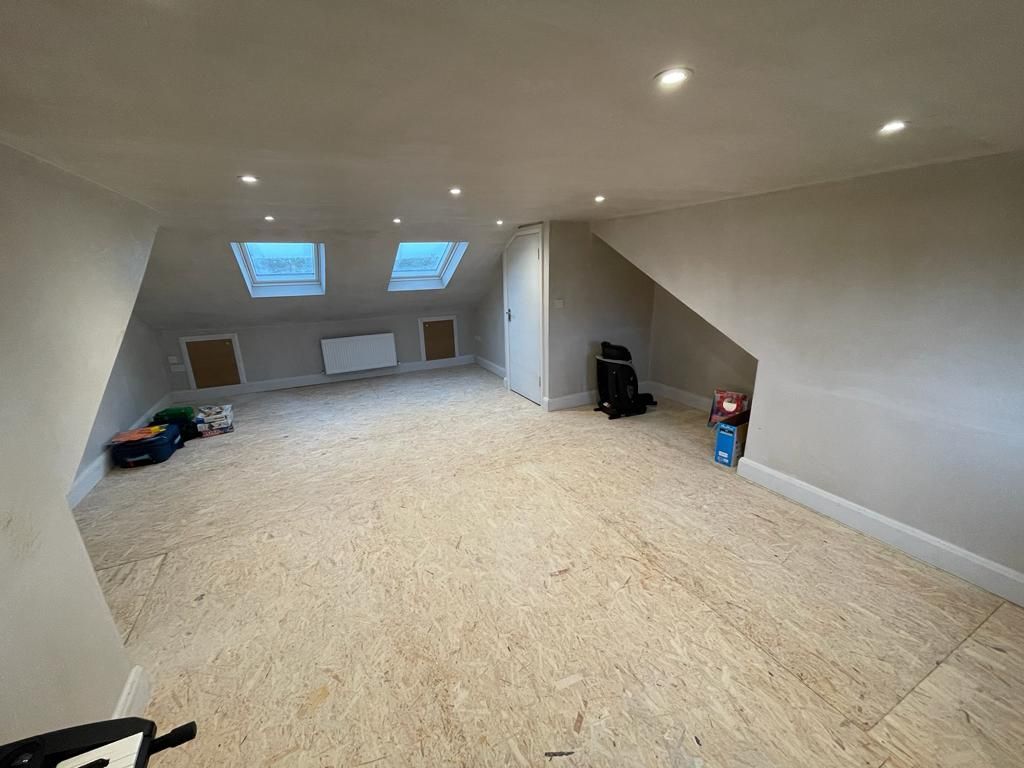 A room with a slanted ceiling and a wooden floor.