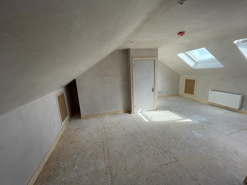 An empty attic with a skylight and a door.