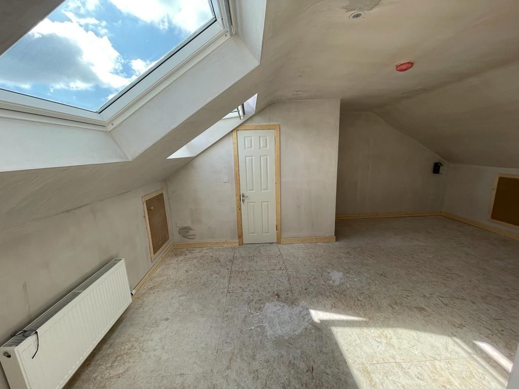 An empty attic with a skylight and a door.
