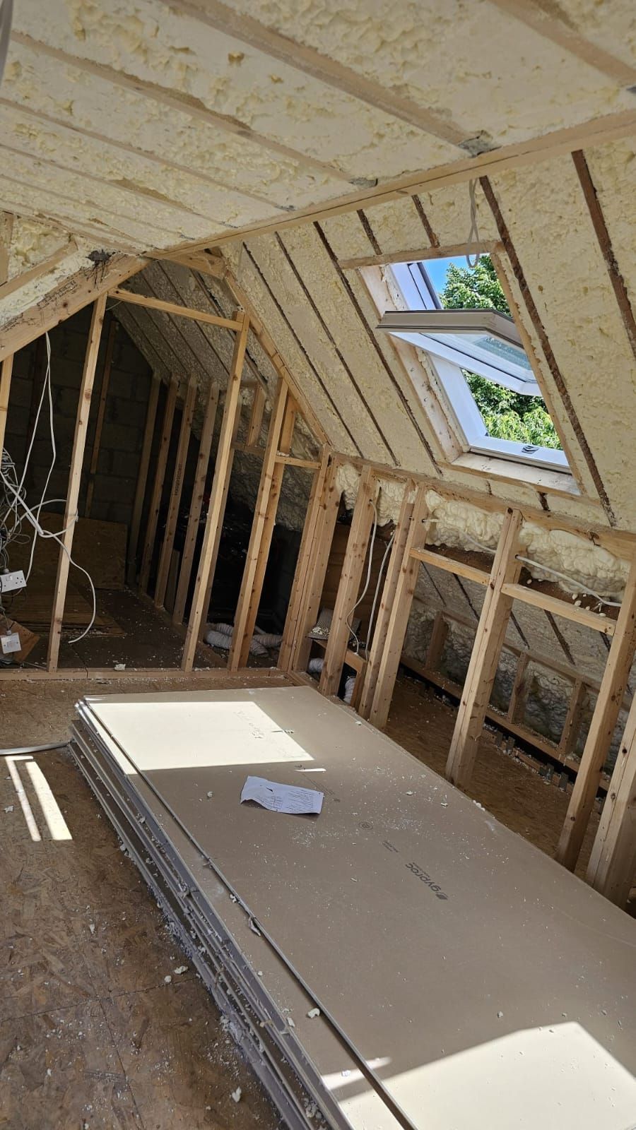 A room in a house under construction with a skylight in the ceiling.